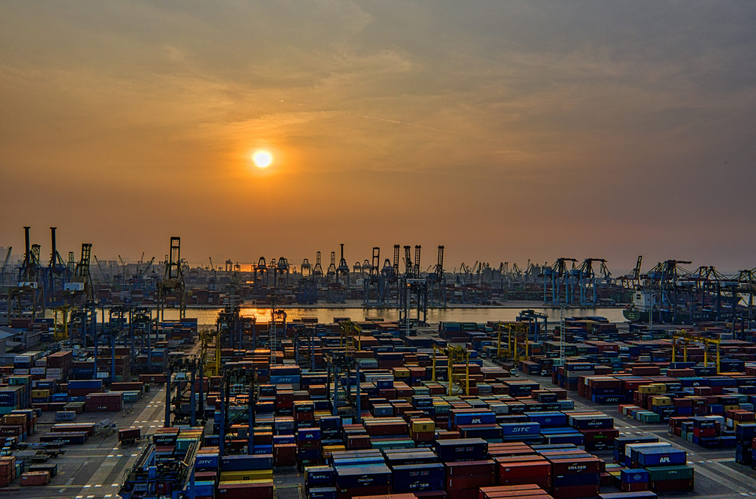 Puesta de sol sobre un puerto de contenedores con smog.